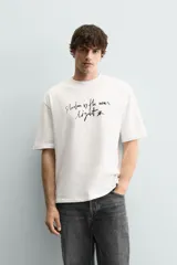 Camiseta de corte relajado confeccionada en algodón, con cuello redondo, manga corta y estampado de texto en contraste en el frente.