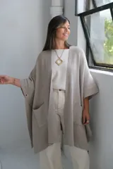 Poncho abierto de tejido de punto en color visón, con diseño holgado, mangas cortas y bolsillos frontales aplicados.