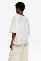 Remera de corte oversize con escote redondo y mangas cortas, confeccionada en algodón con un sutil estampado de textura animal print en tonos neutros.