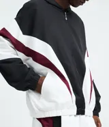 Campera con capucha de estilo deportivo, confeccionada en poliéster con diseño de paneles en colores negro, blanco y bordó. Presenta cierre frontal con cremallera, puños elásticos y bolsillos laterales.