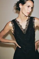 Vestido midi negro confeccionado en encaje de algodón, con escote en pico, diseño sin mangas, forro interior y bajo asimétrico.