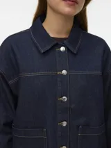 Campera de denim azul oscuro con cierre frontal de botones metálicos, bolsillos frontales aplicados y cuello camisero, de corte recto y holgado.