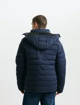 Campera acolchada de color gris, con capucha desmontable, cierre frontal y bolsillos laterales con cremallera. Presenta un diseño de costuras horizontales y detalles en color naranja en los tiradores de los cierres.