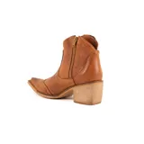 Bota tipo texana de caña baja, confeccionada en cuero vacuno color suela con detalle de cuero con pelo estampado tipo vaca en los laterales. Presenta taco cuadrado de madera y punta fina.