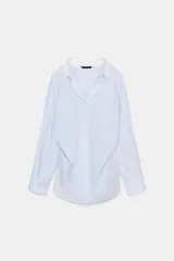 Camisa oversize de algodón con estampado de rayas finas, cuello solapa, escote en pico y manga larga con puños abotonados. Presenta un diseño con pliegues laterales y cierre frontal con botones.
