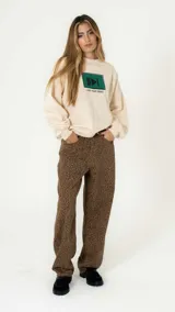 Sweater color beige de corte holgado, con estampa rectangular verde con símbolo de play y texto "Just Keep Going".