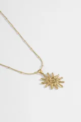 Collar de acero quirúrgico plateado, compuesto por una cadena con pequeñas cuentas intercaladas y un dije colgante en forma de sol con diseño en espiral en el centro.