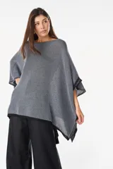 Blusa de punto estilo poncho en color beige, con diseño amplio, cuello redondo y aplique de etiqueta con el logo de la marca en el borde inferior.