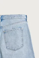 Jeans de denim de algodón color gris con efecto lavado, de corte relaxed barrel fit y tiro medio. Presenta diseño amplio con pinzas en las rodillas y costuras curvas, cierre frontal con botones y cinco bolsillos tradicionales.
