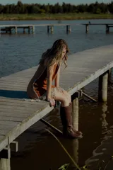 Vestido corto negro sin mangas, con escote en V y detalle de flecos en el ruedo. Presenta bordados en color blanco en el escote, los bolsillos y el centro del vestido.