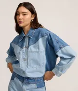 Campera de jean con diseño bicolor, confeccionada en algodón. Presenta cuello polo, cierre frontal con botones, mangas largas y bolsillos aplicados en el frente con recortes estructurados.