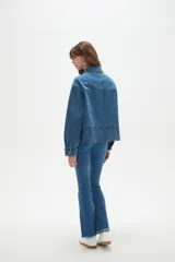 Sobrecamisa de jean azul con cierre frontal de botones metálicos, bolsillos frontales y detalle de bordado inglés en el ruedo.