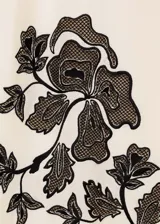 Falda midi de tiro alto con corte evasé, confeccionada en una mezcla de algodón y lino color beige. Presenta un diseño bordado floral en color negro ubicado en el lateral inferior.