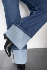 Pantalón de jean corte wide leg en color azul oscuro, con tiro medio-alto y detalle de dobladillo ancho en la botamanga que contrasta con el tono del resto de la prenda.