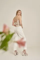 Pantalón de vestir color blanco, de corte recto, con bolsillos laterales y traseros. Se ajusta a la cintura con cinturón de cadena dorada.