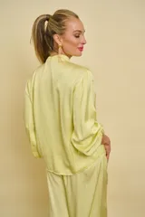 Blusa de satén color amarillo claro con escote en V y cuello de lazo ajustable. Presenta mangas largas holgadas con puños elásticos y diseño fluido.