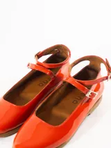 Chatas rojas de cuero charol, con pulsera al tobillo con hebilla y suela color caramelo.