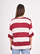 Remera de corte holgado con diseño de rayas horizontales anchas en tonos azul y blanco, cuello redondo y mangas cortas.