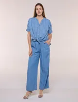 Blusa de silueta amplia de lyocell color azul con diseño de rayas verticales blancas. Cuenta con cuello mao abierto, abotonadura frontal, mangas cortas caídas y lazos en el ruedo para anudar al frente.