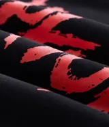Buzo con capucha de corte relajado, color negro, con estampado frontal y en la manga con el logo de la banda Slipknot en tonos rojos y azules.