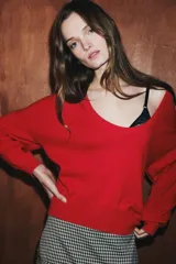 Jersey de punto liso color rojo, con escote en V profundo y mangas largas. Presenta terminaciones en rib en el cuello, puños y ruedo.