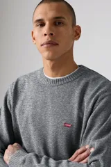 Sweater de tejido de punto gris jaspeado, con cuello redondo, mangas largas y puños y ruedo acanalados. Presenta el logo de la marca bordado en pequeño en el pecho.