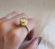 Anillo dorado con dije irregular con forma de piedra.