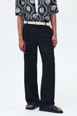 Pantalón sastrero de sarga en color negro, con corte holgado, piernas amplias con raya marcada, cierre frontal con botón y corchete ocultos, bolsillos al bies y bolsillos traseros insertados.