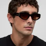 Lentes de sol con montura geométrica tipo cat-eye de color negro y cristales polarizados en tono marrón.