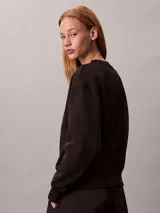 Buzo de felpa Calvin Klein de color negro, corte regular y cuello redondo, con el nuevo emblema con logo texturizado en el pecho y puños, cuello y bajo de canalé.