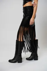 Falda midi negra de cuero sintético con flecos largos y abertura lateral.