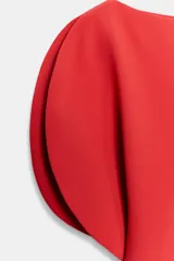 Vestido midi de cuello barco y manga corta abullonada, color rojo, con diseño asimétrico en el bajo en línea evasé y cierre trasero con cremallera oculta.