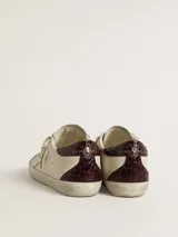 Zapatillas urbanas Golden Goose modelo Super Star, color blanco con detalles en marrón y estrella dorada. Diseño con efecto desgastado y suela de goma.