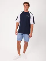 Remera holgada Rusty modelo Isel, de diseño bicolor con cuerpo azul marino y mangas ranglán blancas. Cuenta con cuello redondo ribeteado y pequeño logo bordado en el pecho.