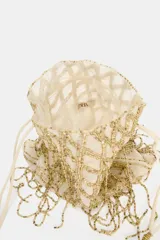 Bolso tipo saca de color crudo con cuerpo cubierto de lentejuelas doradas formando un patrón de red con flecos colgantes. Posee doble asa de hombro y cierre mediante fruncido.