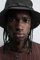 Camiseta de algodón de corte relajado (relaxed fit) color marrón oscuro, con cuello redondo y manga corta. Presenta una textura acanalada vertical tipo jacquard.