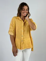 Camisa color beige de lino con cuello clásico, abotonadura frontal y mangas 3/4 con botón.