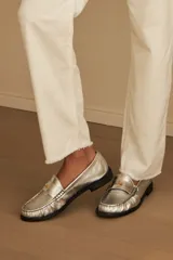 Mocasín de cuero con textura efecto cocodrilo en color plateado, con herraje metálico dorado con logo VDM y suela plana oscura.