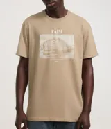 Remera de manga corta color beige claro, con cuello redondo y estampa rectangular frontal con un carpincho en el agua.