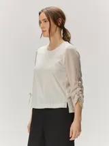 Remera de manga larga color blanco con cuello redondo y detalles fruncidos con lazos en las mangas.