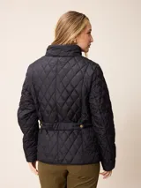 Campera acolchada de diseño matelassé, color negro, con cuello alto, cierre frontal con cremallera y botones a presión, y bolsillos delanteros con solapa.