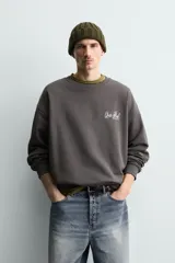 Sudadera gris oscuro de corte relaxed fit, cuello redondo y manga larga, con estampa en contraste en el pecho y acabados en rib.