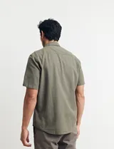 Camisa sport de manga corta, confeccionada en una mezcla de lino y algodón. Presenta cuello clásico, cierre frontal con botones de coco y un bolsillo aplicado en el pecho.