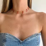 Gargantilla doble con cuentas rojas y detalles dorados.