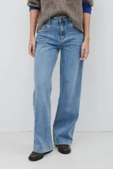 Pantalón jean de tiro alto y corte wide leg, en color azul medio con lavado clásico, bolsillos delanteros y traseros, y cierre frontal con botón y cremallera.