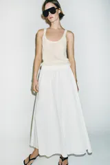 Falda midi de corte en A, color blanco, confeccionada en algodón con cintura elástica de tiro alto y forro interior a tono.