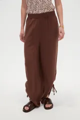 Pantalón verde militar de corte ancho y tiro alto, con cintura elástica fruncida y detalles de cordones ajustables en los tobillos.