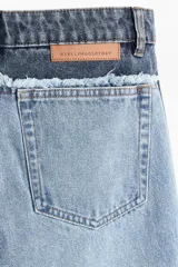 Jean de corte holgado y pierna recta confeccionado en denim de algodón rígido. Presenta un diseño bicolor con paneles en tonos contrastantes, costura desflecada en la cintura y franjas laterales. Cuenta con diseño de cinco bolsillos, cierre con botón y tachas metálicas con logo grabado.