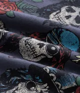 Remera de algodón color gris azulado, con cuello redondo y manga corta. Presenta un estampado gráfico frontal con el logo de la banda Guns N' Roses y calaveras rodeadas de rosas.