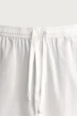 Pantalón de corte relajado confeccionado en una mezcla de algodón y lino. Presenta cintura elástica con cordón ajustable, bolsillos laterales y bolsillos traseros de vivo.